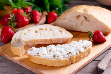 Freshly baked sliced bread on wood cutting board with cottage cheese
