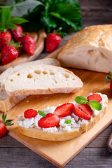 Bruschetta with strawberries, cottage cheese and mint on a cutting board