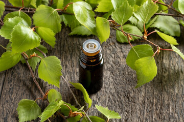 A bottle of essential oil with birch branches