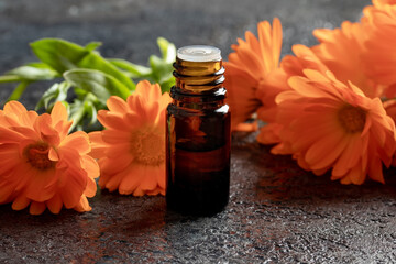 A bottle of calendula essential oil with calendula flowers