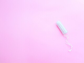 Women's hygiene intimate accessories. A clean white tampon on a pink background. Menstrual cycle. Space for text.