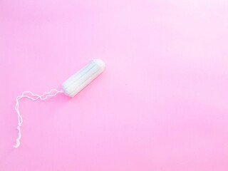 Women's hygiene intimate accessories. A clean white tampon on a pink background. Menstrual cycle. Space for text.