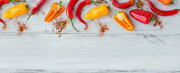 Top view of assorted spices and colorful peppers on white wooden table. Seasonings background with...