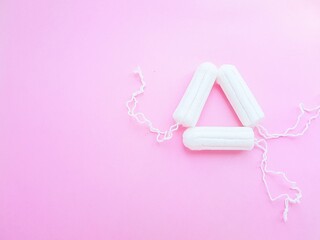 Women's hygiene intimate accessories. A clean white tampon on a pink background. Menstrual cycle. Space for text.