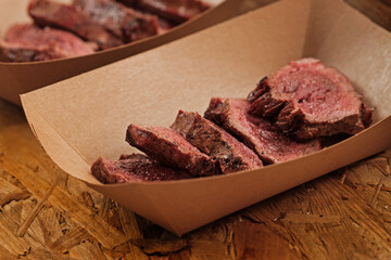 Delicious beef slices in craft paper container on street food festival