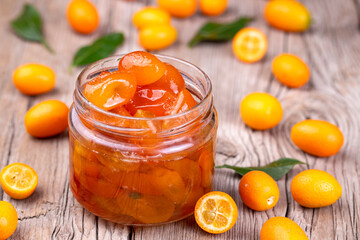 Homemade kumquat jam in jar and fresh kumquats, top view - obrazy, fototapety, plakaty