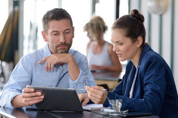 man and woman having business meeting in cafe using tablet