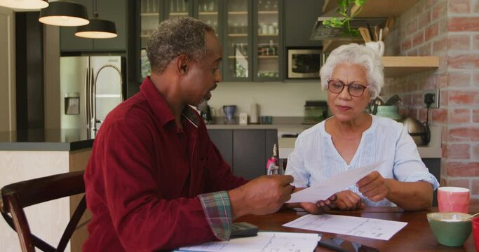 Senior African American husband and mixed-race wife working together at home