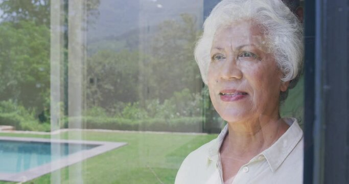 Senior African American husband and mixed-race woman looking at their window, reflection of the wind