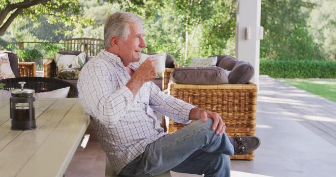 Senior Caucasian man spending time and drinking a beverage in the garden