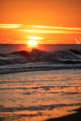 Fototapeta premium Looking across the ocean at the setting sun dip underneath the horizon line. Long Island NY