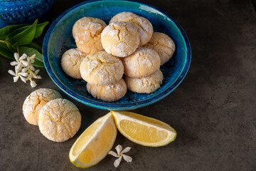 lemon cookies and slices of lemon on a dark table with small white flowers