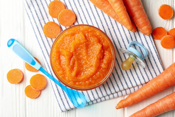 Composition with carrot puree on white wooden background. Baby food