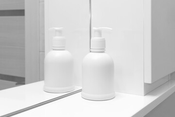 Fototapeta na wymiar Sanitizer or antiseptic gel for washing hands. Prevent disease, virus protection concept. Pure white bottle stands in the bathroom by the mirror. Hygiene, the warn of germs and bacteria.