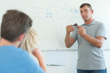 driving school teacher showing a motorbike model