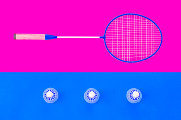 Badminton background. Badminton racquet on magenta background and three shuttlecock on blue background. Top view. 