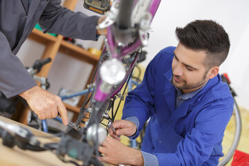 bicycle mechanic and apprentice repairing a bike in workshop
