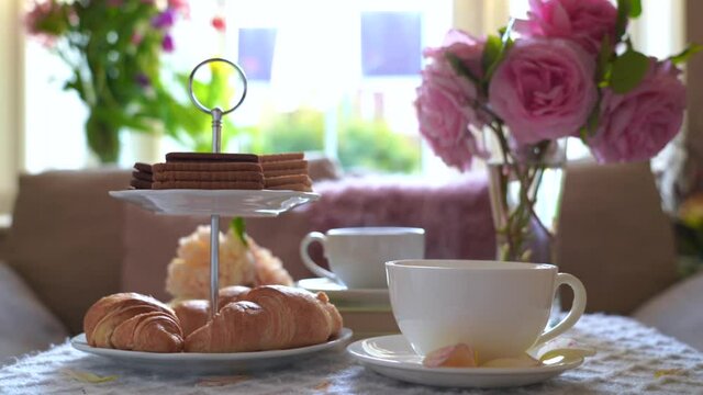 Traditional English tea time, Afternoon tea ceremony with steaming couple tea cup, croissants, crackers and biscuits on hight tea stand,Cozy sence of afternoon party in conservatory room