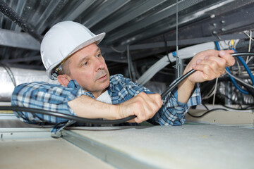worker wiring cables on the ceiling