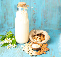 on a blue wooden background different almonds and milk in a glass bottle