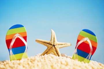 Beach summer vacation. Bright flip-flops and starfish on the sand against the background of the...