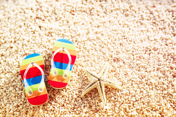 Travel background with bright flip-flops and starfish on the sand closeup, top view. Beach summer vacation. 