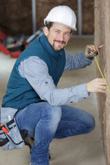 tradesman measuring wall packed with insulation