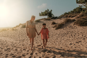 mother and daughter walking on the sand