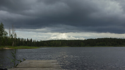 Dark Overcast Sky With Thunderclouds Over The Forest Lake