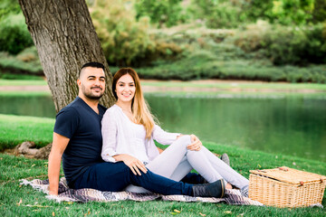 Young woman and man spending their time at the park, having a picnic.