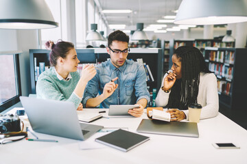 Coworkers discussing startup project while checking information using modern digital devices and wireless connection