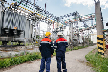 Two specialist electrical substation engineers inspect modern high-voltage equipment. Energy. Industry