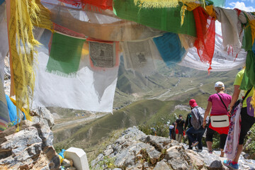 Group of tourists taking a hike around Drepung monastery near Lhasa, Tibet, walking underneath prayer flags