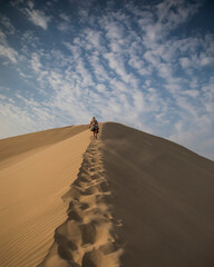 Fototapeta na wymiar woman climbing a dune in the desert