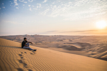 Fototapeta na wymiar man sitting on a top of a dune