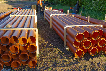 orange sewer pipes at a construction site. Underground orange plastic pipes. Stacked PVC orange...