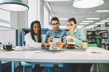 University classmates cooperating preparing for examination in library