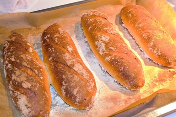 Artistic composition in intense artificial light. Ruddy crispy homemade baguettes in flour, on...