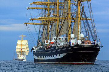 Sailing ships with bulging sails participating in a sailing regatta.