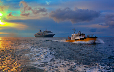 Cruise ship leaves the port, accompanied by a pilot boat.