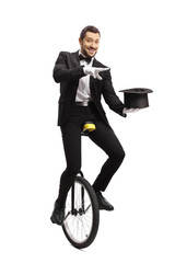 Magician riding a mono-cycle and performing a magic trick with a hat © Ljupco Smokovski