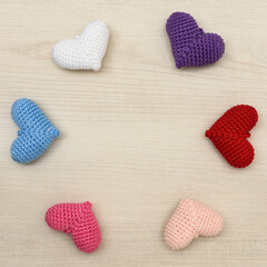 Colorful crochet hearts on a wooden background.