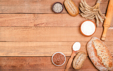 Bakery - various rustic crisp loaves of bread and rolls, wheat flour, a bunch of spikelets on wooden boards.