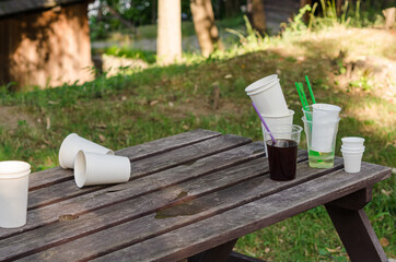 Empty dirty plastic and disposable cups, left on a wooden table, after have been used.