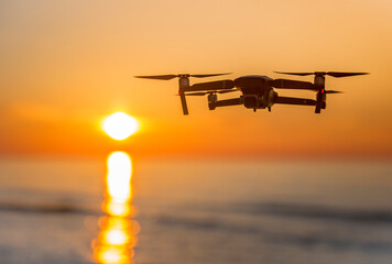 Lecący dron na tle zachodzącego słońca - obrazy, fototapety, plakaty