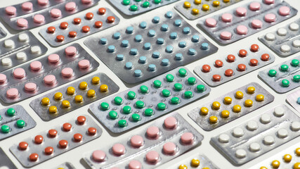 Composition with many medical pills, tablets pack in blister lying diagonally over white background. Health care, vitamins and treatment concept