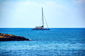 Fototapeta premium Little yacht sailing during summer day along coastline of Cambrils, Spain.