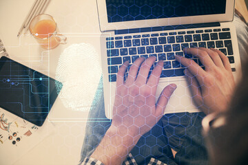 Double exposure of man's hands typing over computer keyboard and finger print hologram drawing. Top view. Personal security concept.