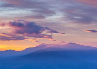 Amazing summer sunrise in the mountains. Colored clouds envelop mountain peaks. Carpathians, Ukraine.