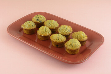 Mini blueberry muffins on red brunch plate on pink background